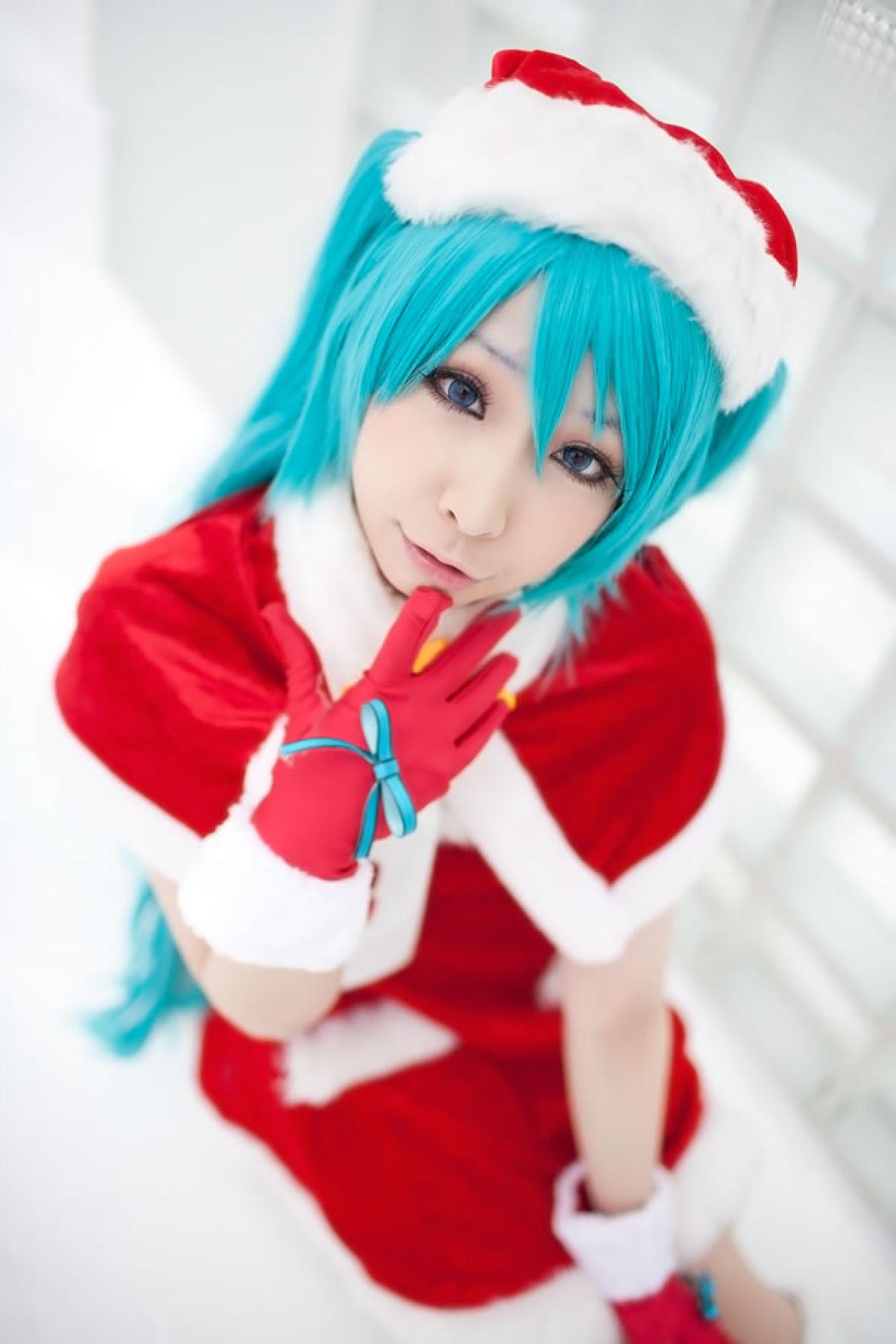 Miiko穿着初音圣诞礼服一只手的食指抵住下巴，嘟着嘴卖萌