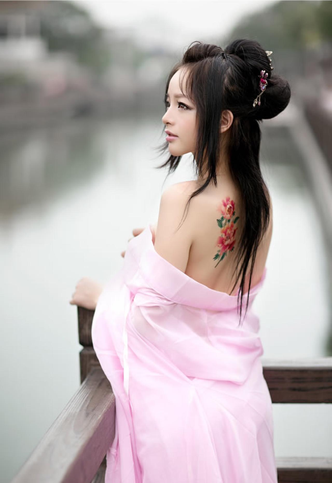 歪歪穿着粉色绸缎扶着木栏杆眺望湖水，背面印着两朵鲜花