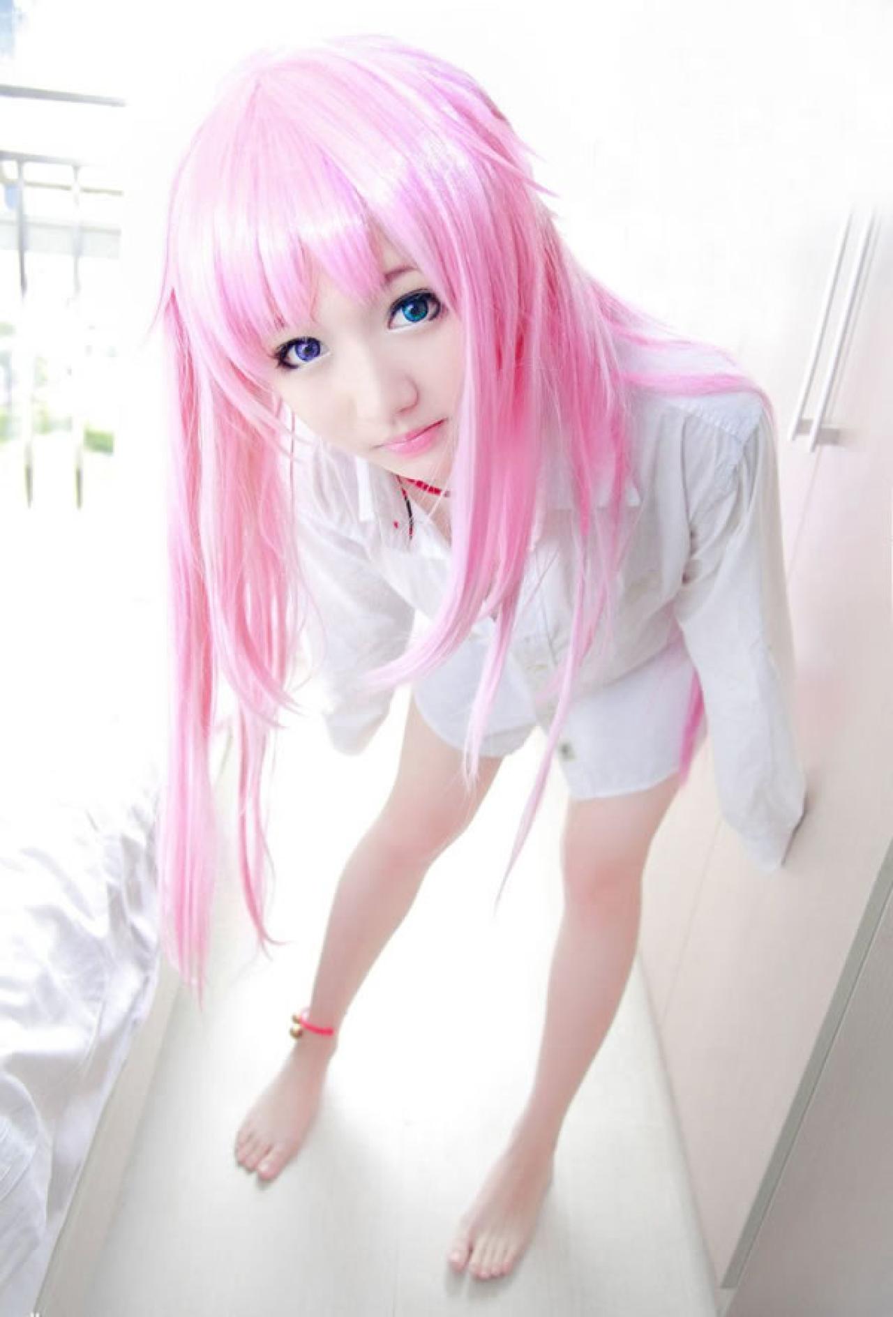 摆摆扮演《K》粉色猫娘，只穿着白衬衫，站在床旁的过道的地板上，前倾身体的样子