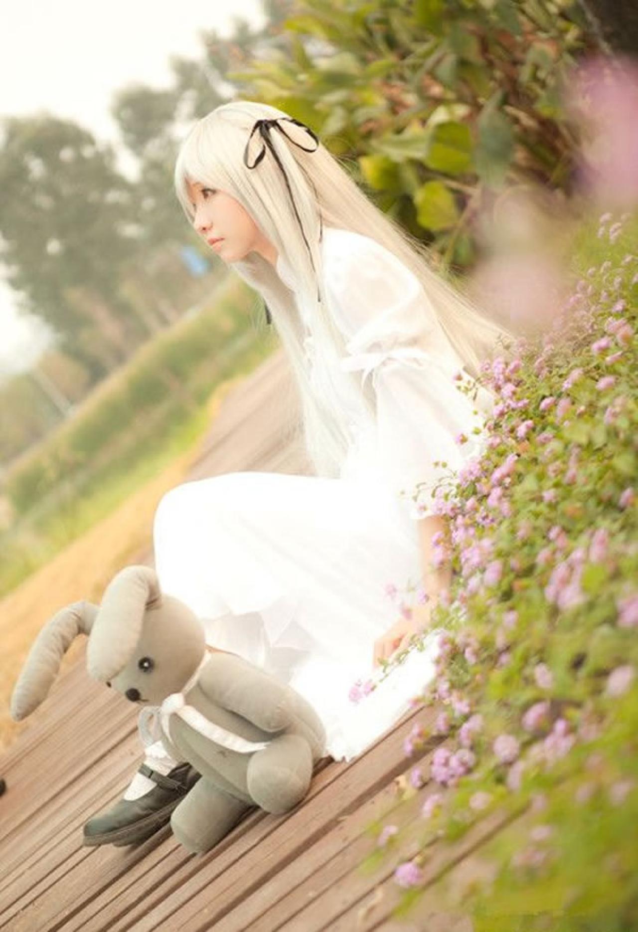 哀子扮演穹妹穿着白色连衣裙坐在木板上靠着芦苇丛