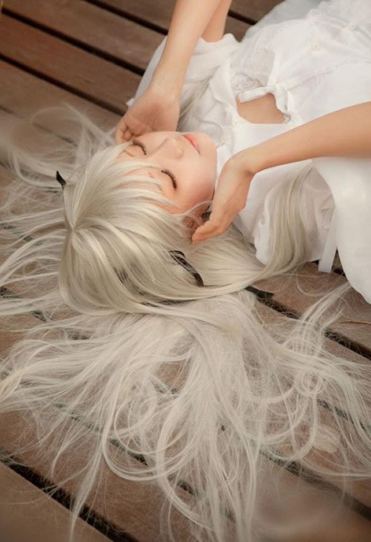 哀子扮演穹妹穿着白色连衣裙躺在木板上，双手扶着耳朵倾听