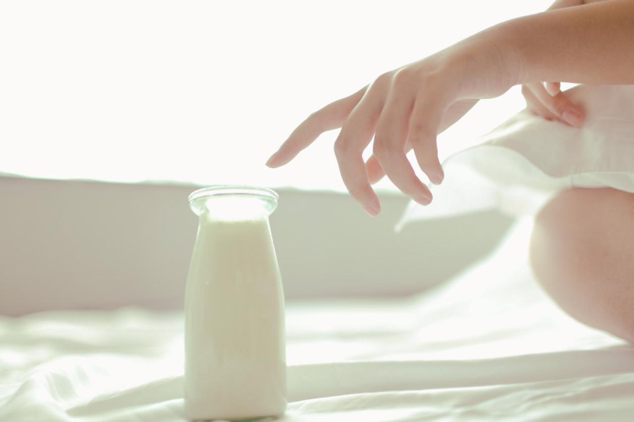 奈音蘑菇抱着枕头，伸手去拿一杯牛奶