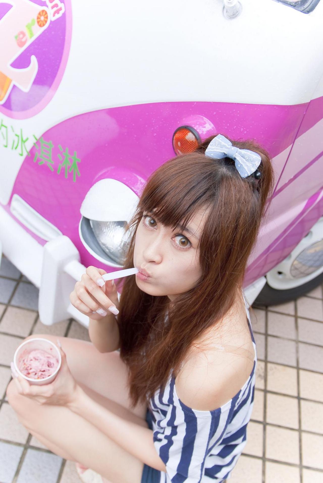 璟儿蹲在粉色小轿车旁，嘟嘴咬着冰淇淋的小勺