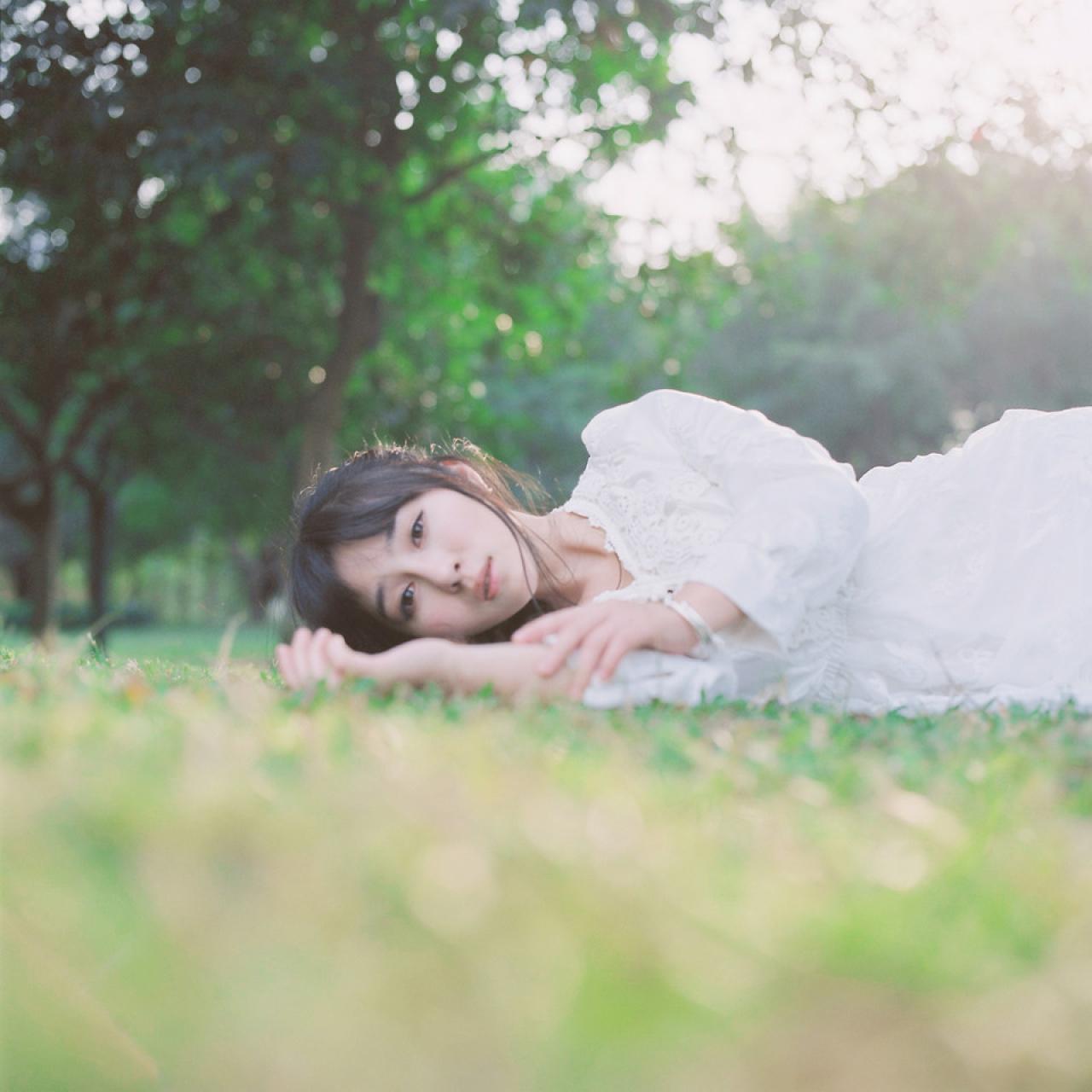 萌少女侧身躺在青黄交接的草地上