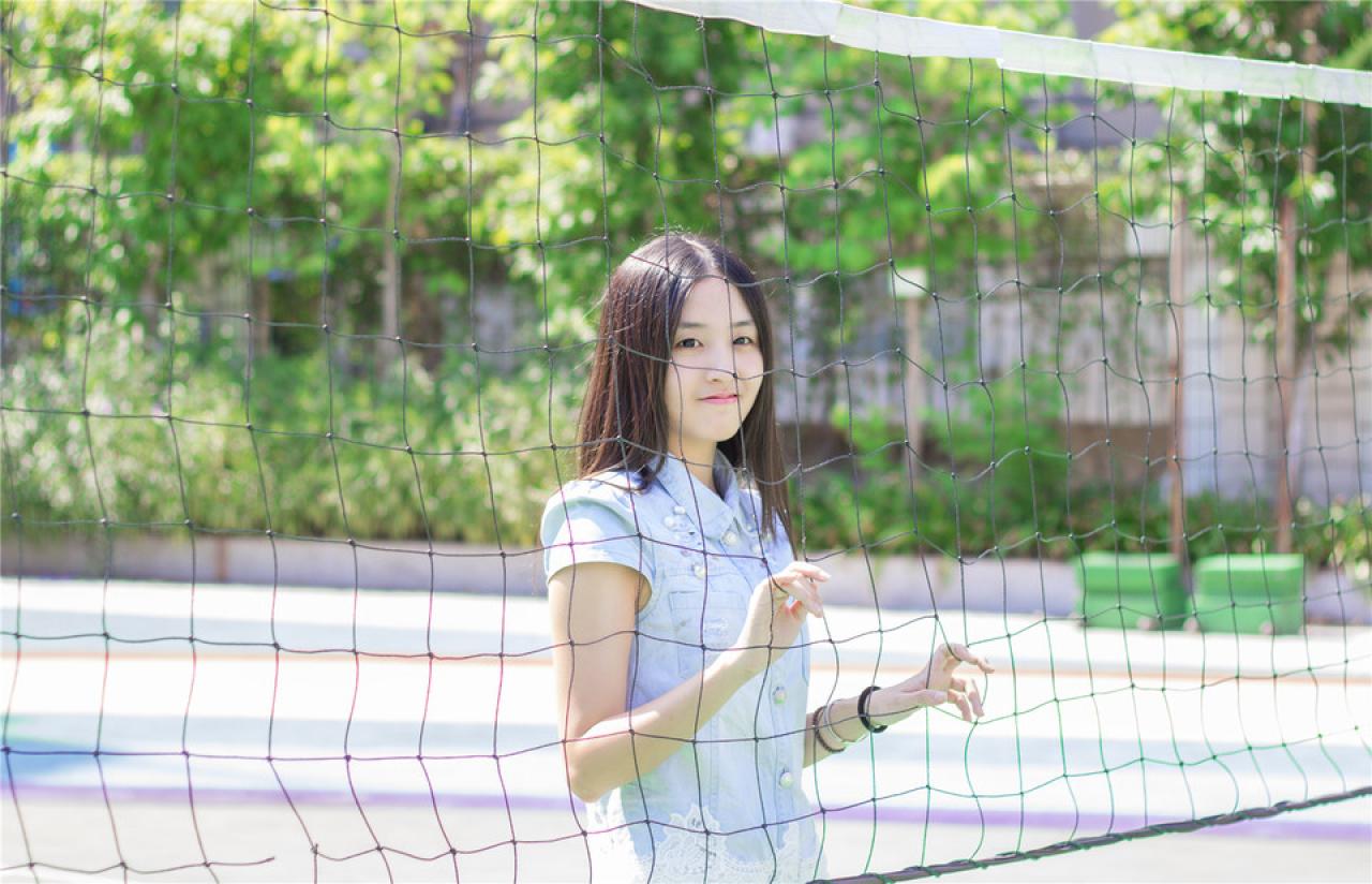 陈婕扒在球网后，微笑神情，上半身，侧面照