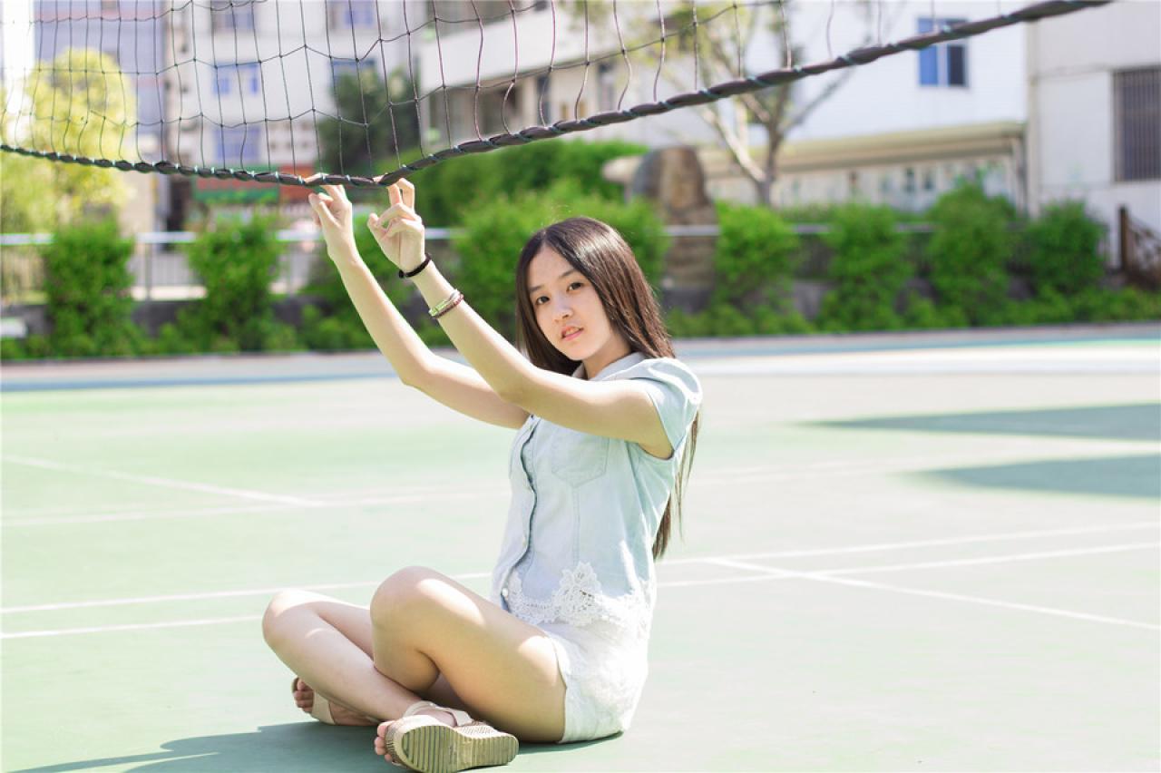 陈婕坐在球网下，双手食指和中指搭在球网底边上