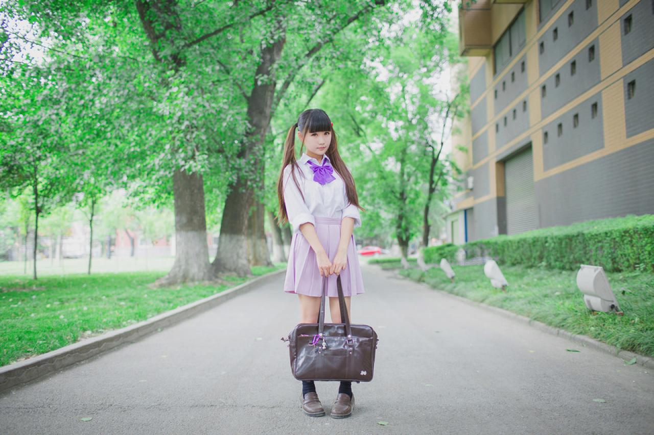 紫色制服萌妹子拎着通勤包站在校园路上