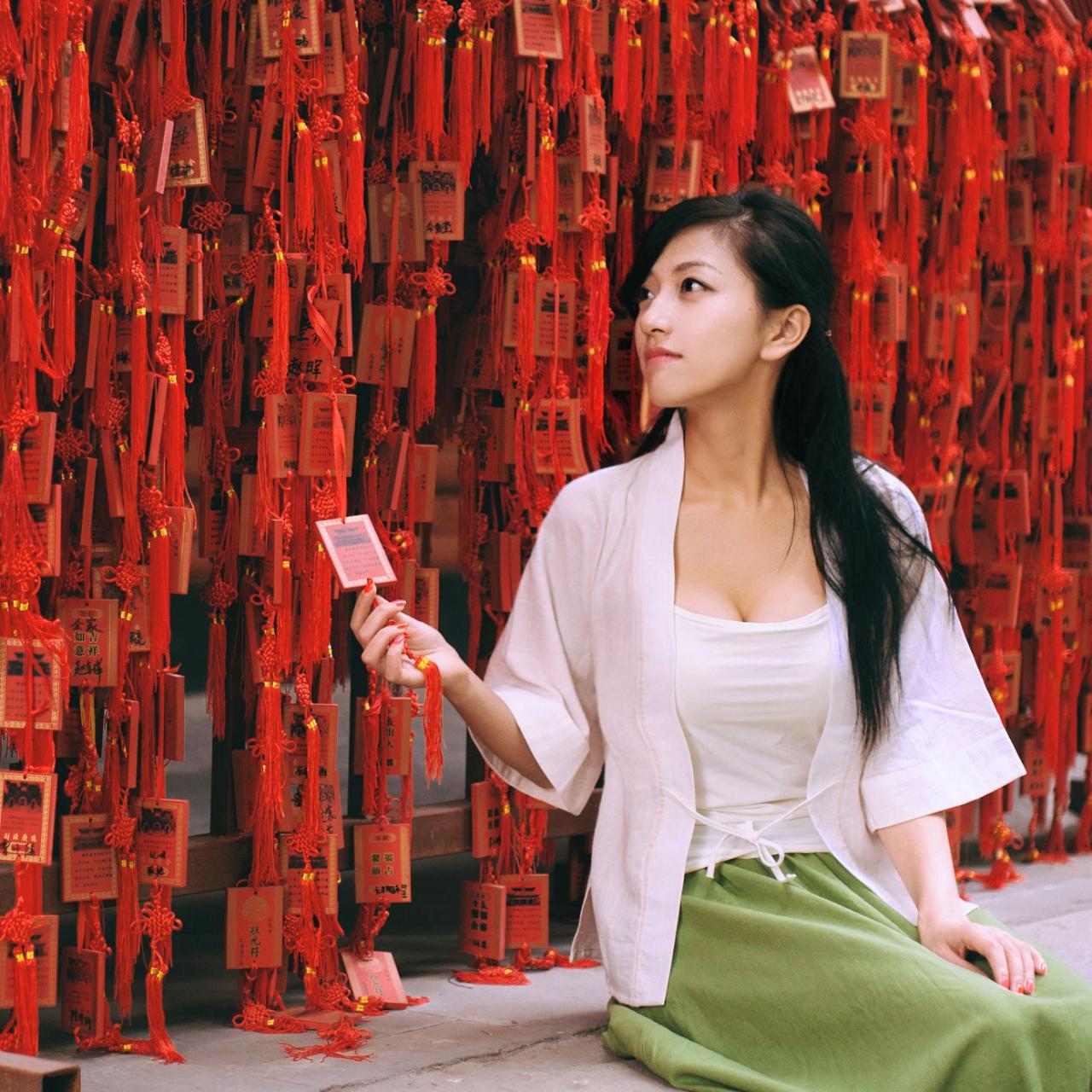 语希范坐在连在一起的中国结前，侧身挂上写着祝福的牌子