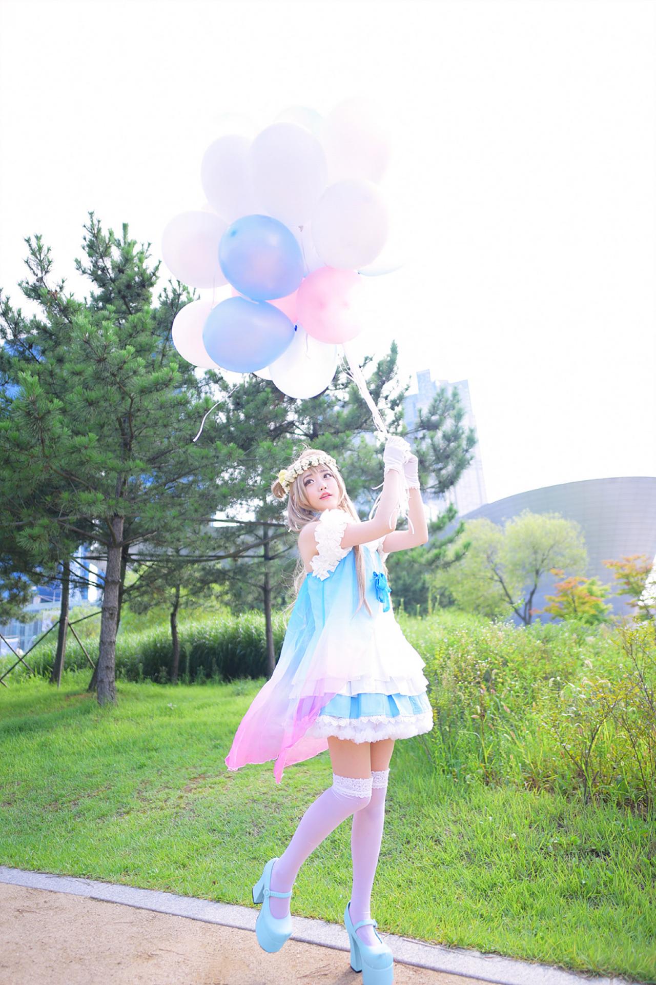 兔娘tomia扮南小鸟站在草地旁的小路上，双手握着气球