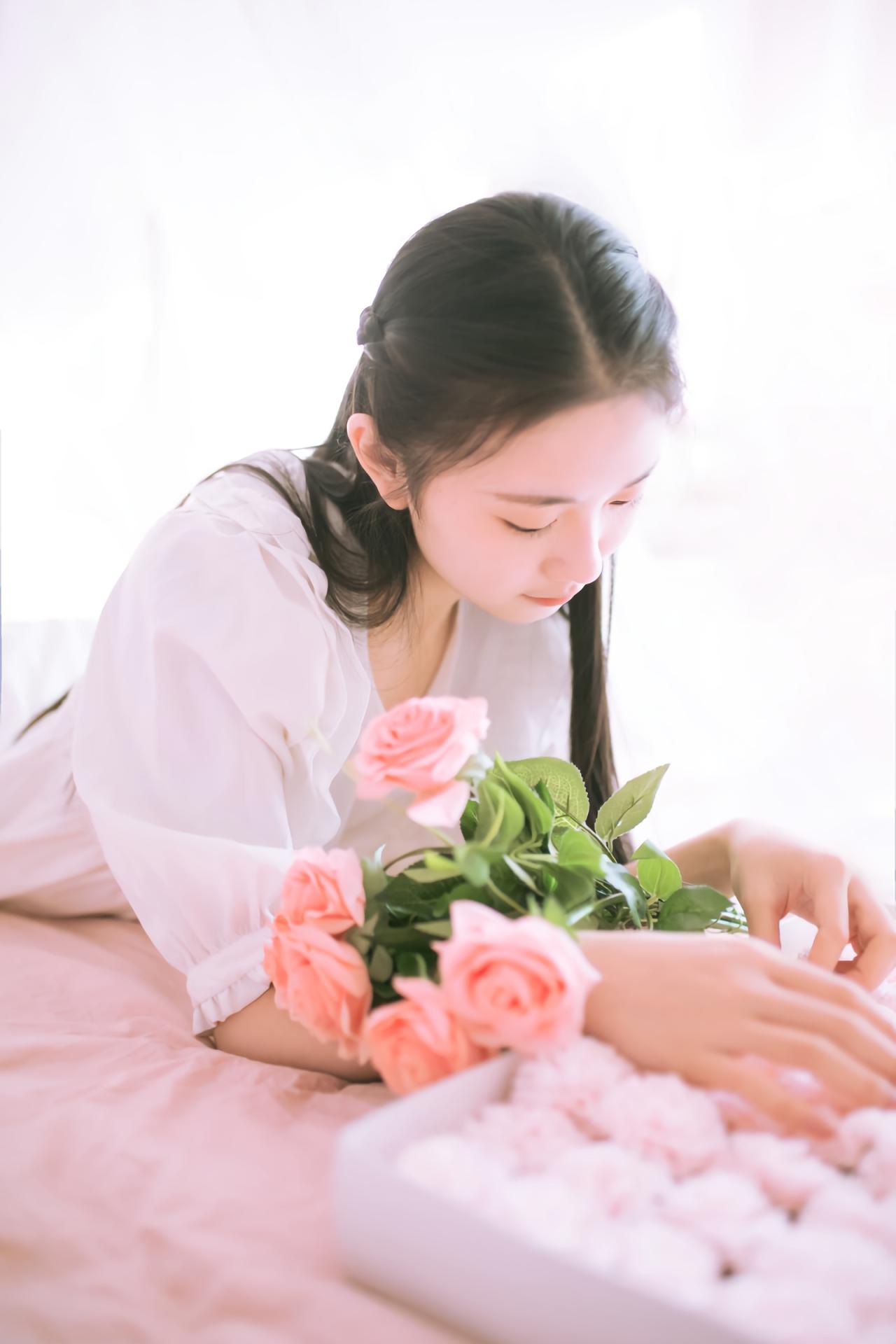 黑长直萌妹子趴在床上 手臂上放着粉色鲜花 整理鲜花礼盒