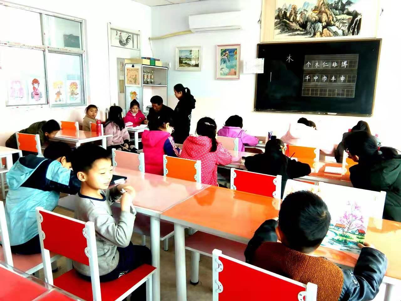 老师正在给圆梦画室硬笔书法二班的学生辅导课堂作业